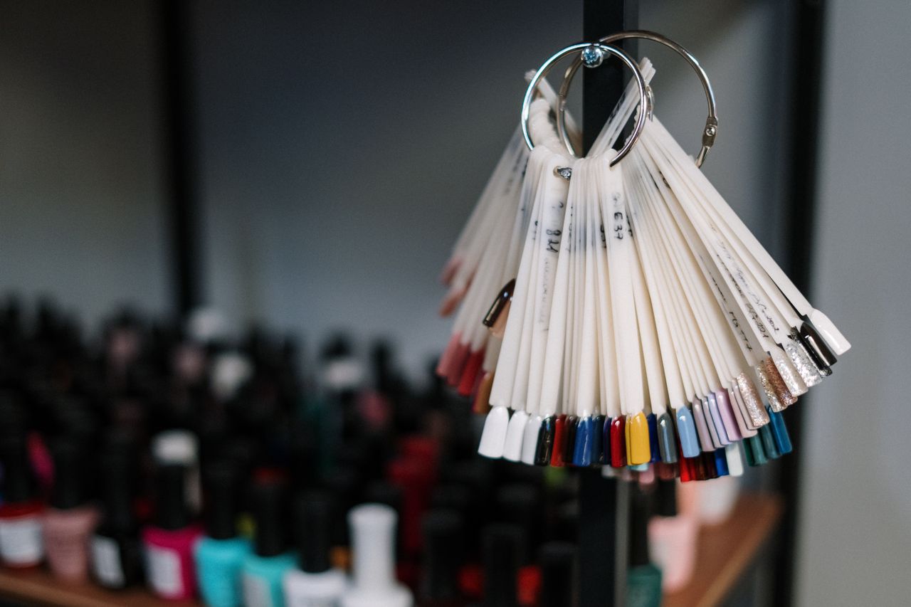 Colorful nail polish samples on display in a modern beauty salon, flanked by assorted bottles.