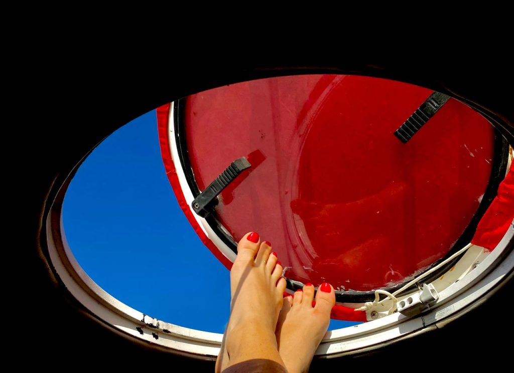Close-up of a womans feet with pedicure through an airplane window on a bright day.